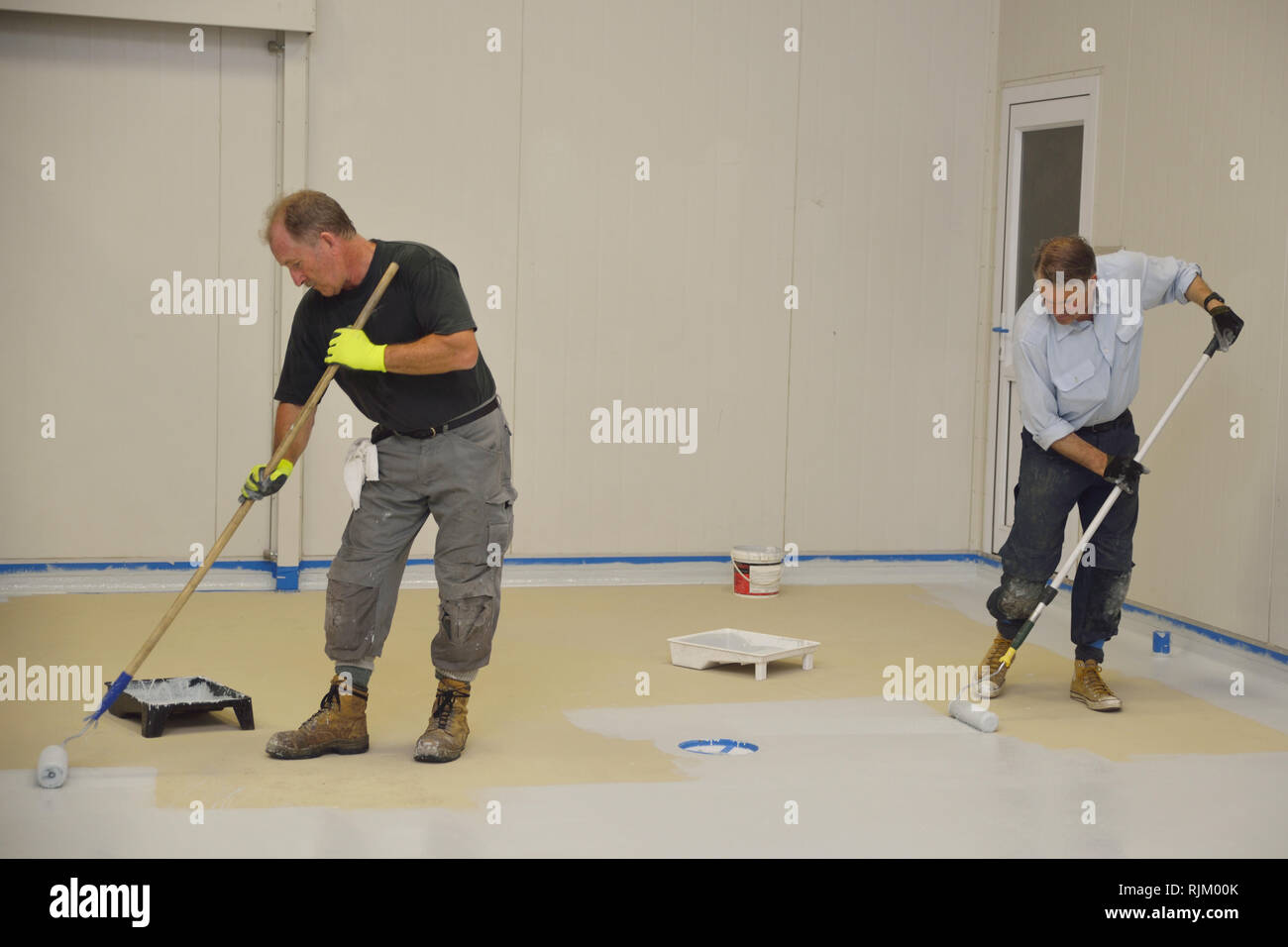 La dernière couche de roulement de métier d'epoxy produit sur le plancher d'un bâtiment industriel Banque D'Images