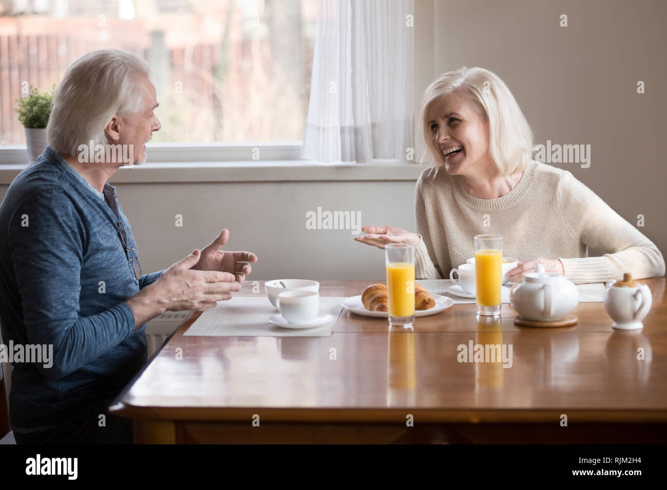 Vieux couple s'amusant rire assis manger le petit déjeuner dans la cuisine Banque D'Images