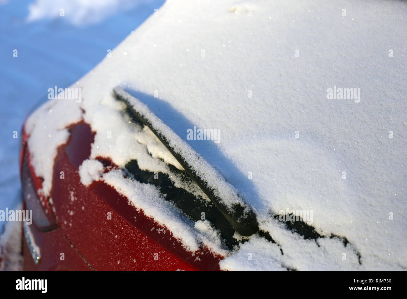 La neige sur le haut de la fenêtre arrière d'une voiture rouge. Photographié de jour durant l'hiver en Finlande. Banque D'Images