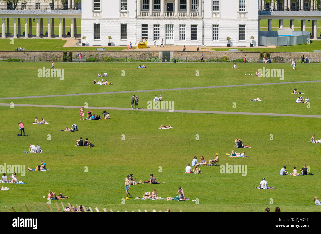 Des foules de gens se coucher sur l'herbe et profiter du soleil et de la chaleur pendant une vague dans le parc de Greenwich, Londres, Angleterre. Banque D'Images