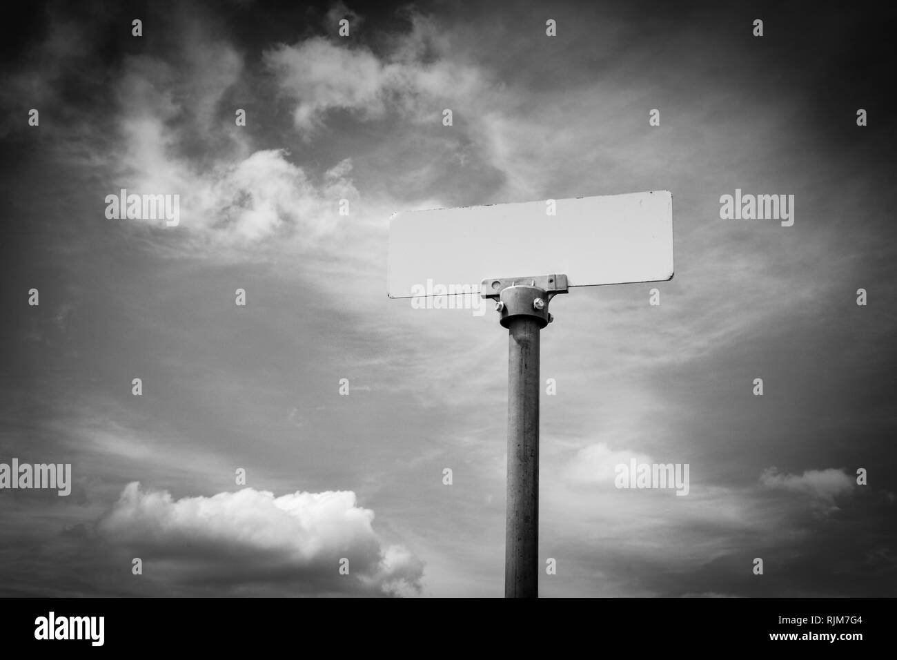 Un mystérieux nom aucun signe de métal sur un poteau, semblable à un nom de rue signe, monte jusqu'à rencontrer un ciel dramatique, apparemment avec un message inconnu Banque D'Images