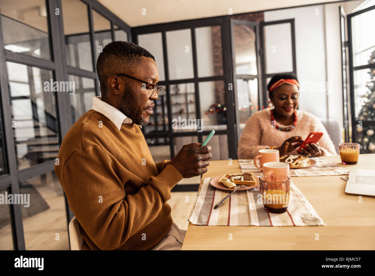 Bel homme sérieux en utilisant son nouveau smartphone Banque D'Images