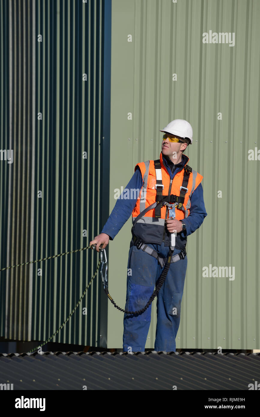 Un constructeur de porter un harnais de sécurité tout en travaillant à des hauteurs attend des instructions du contremaître Banque D'Images