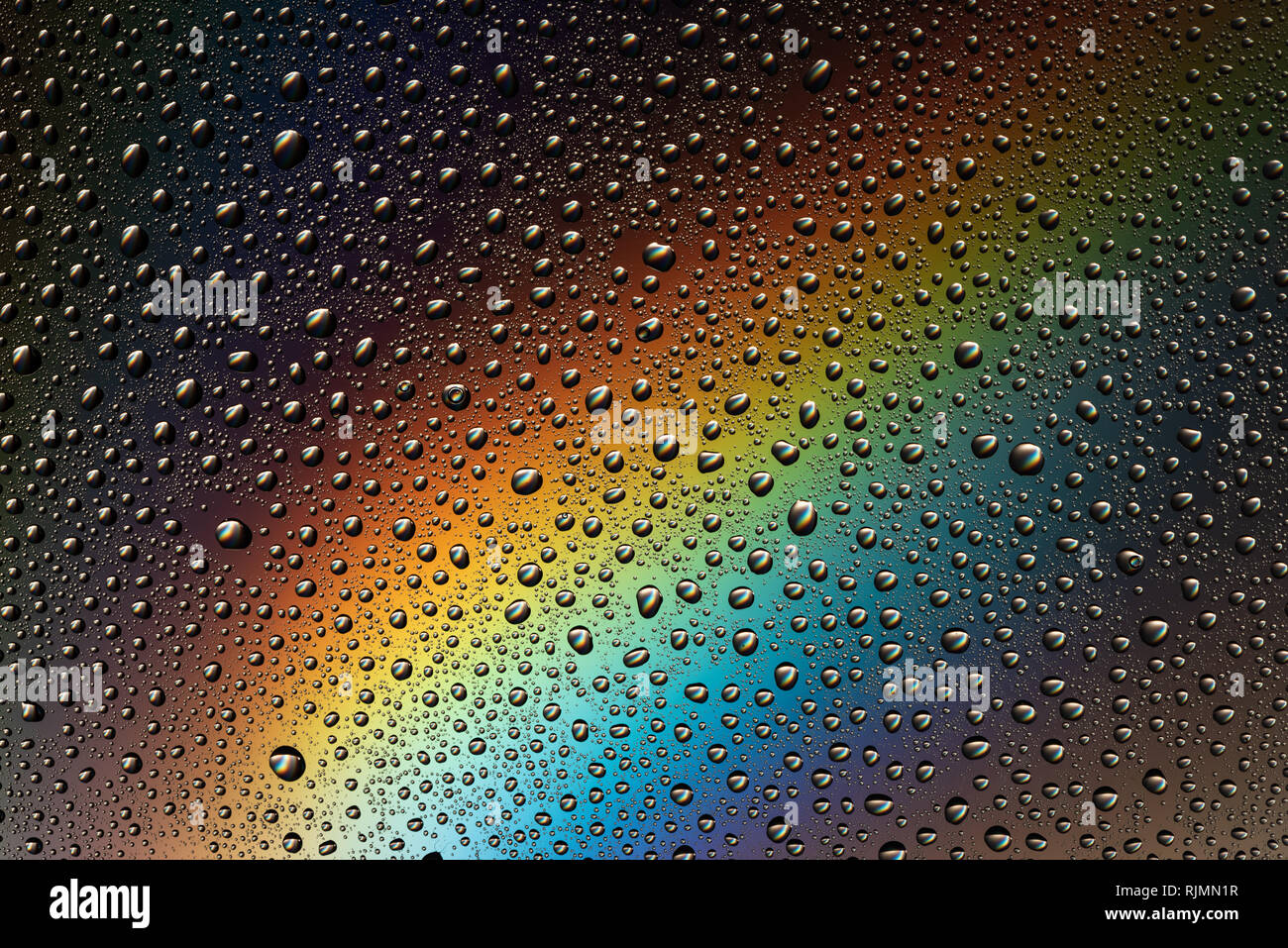 Gouttes d'eau sur la vitre à la lumière de l'arc en ciel. L'Abstraction. L'arrière-plan. Banque D'Images