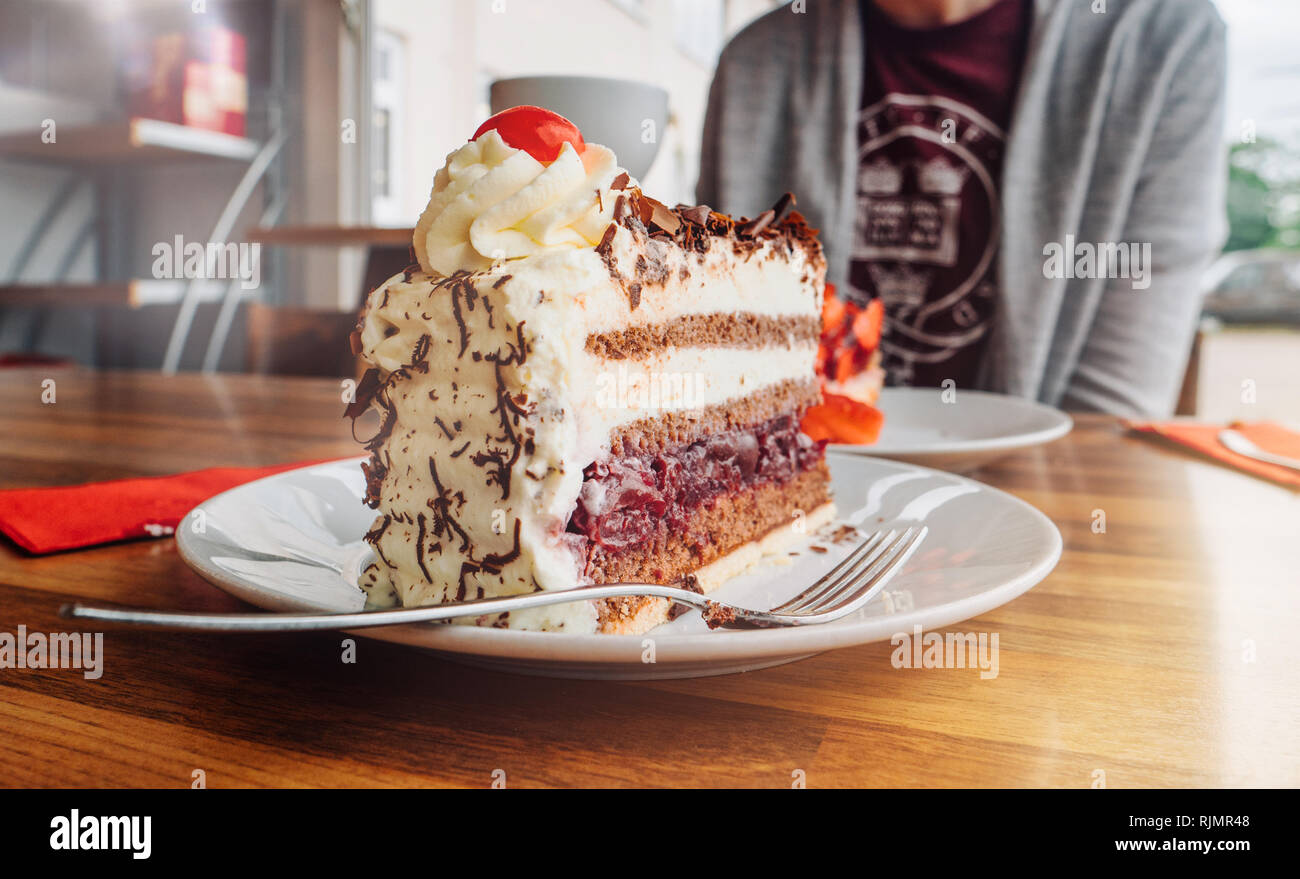 Femme De Delicieux Dessert Aux Fraises Et Foret Noire Gateau Schwarzwalder Kirschtorte Allemand Avec Tasse De Cafe Dans La Cafeteria Photo Stock Alamy