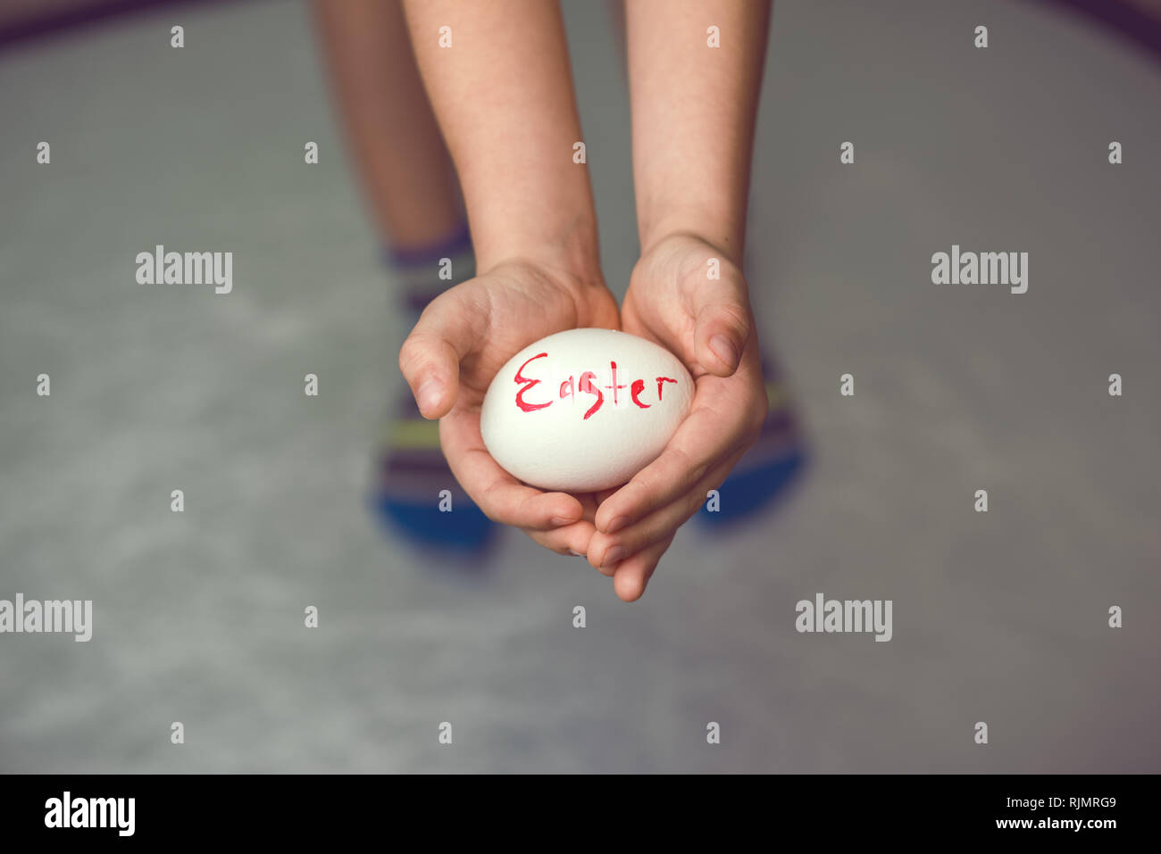 Les œufs avec l'inscription Joyeuses Pâques l'enfant tient dans ses mains devant lui. Banque D'Images