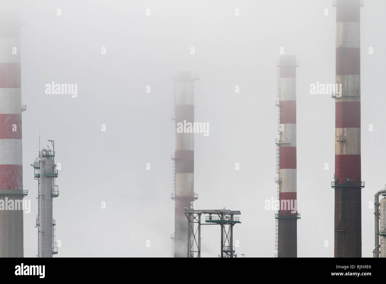 Les cheminées de la raffinerie de pétrole et des tours entre le brouillard Banque D'Images