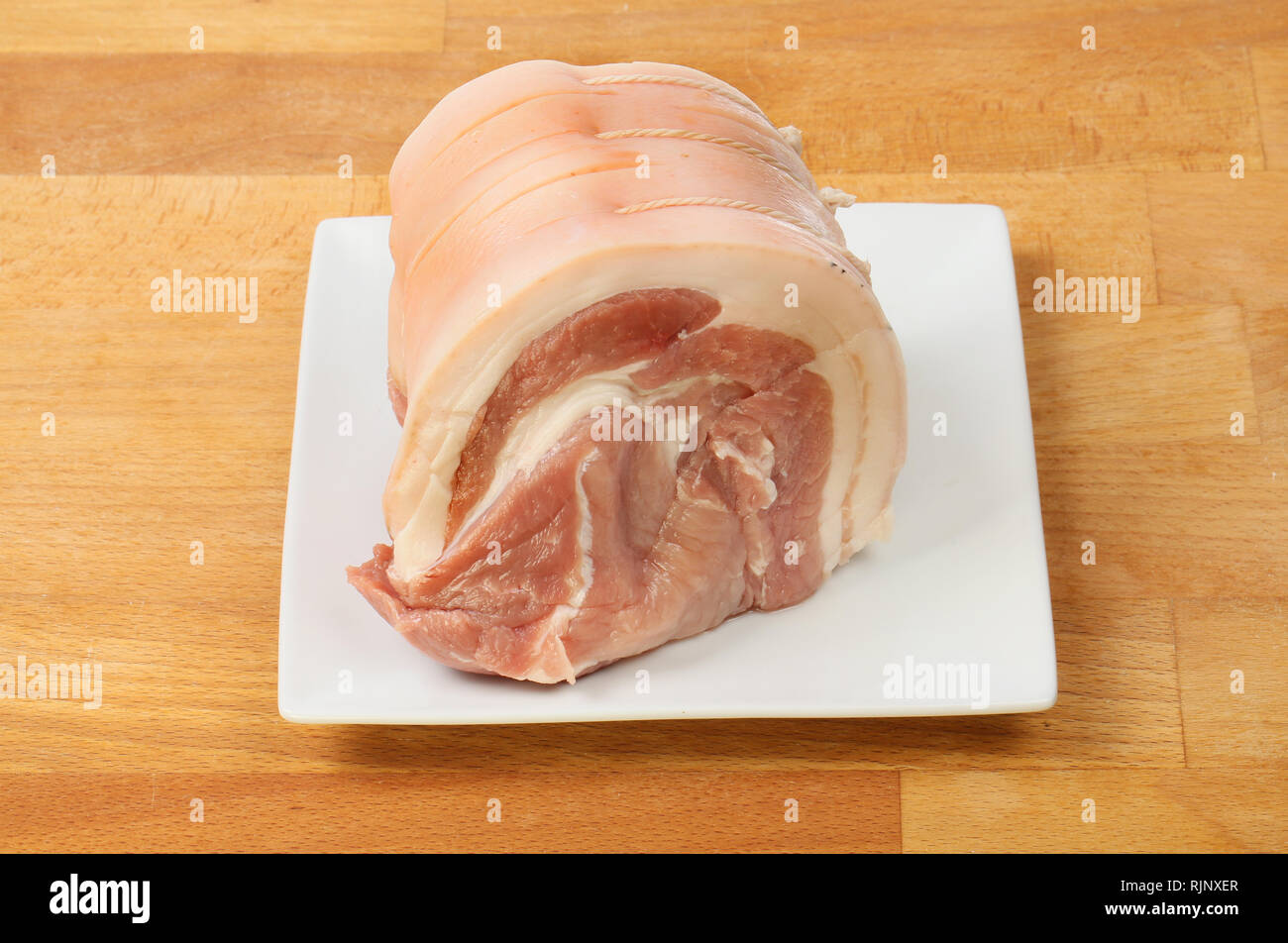 Longe de porc cru mixte de viande sur une plaque sur un plan de travail en bois Banque D'Images