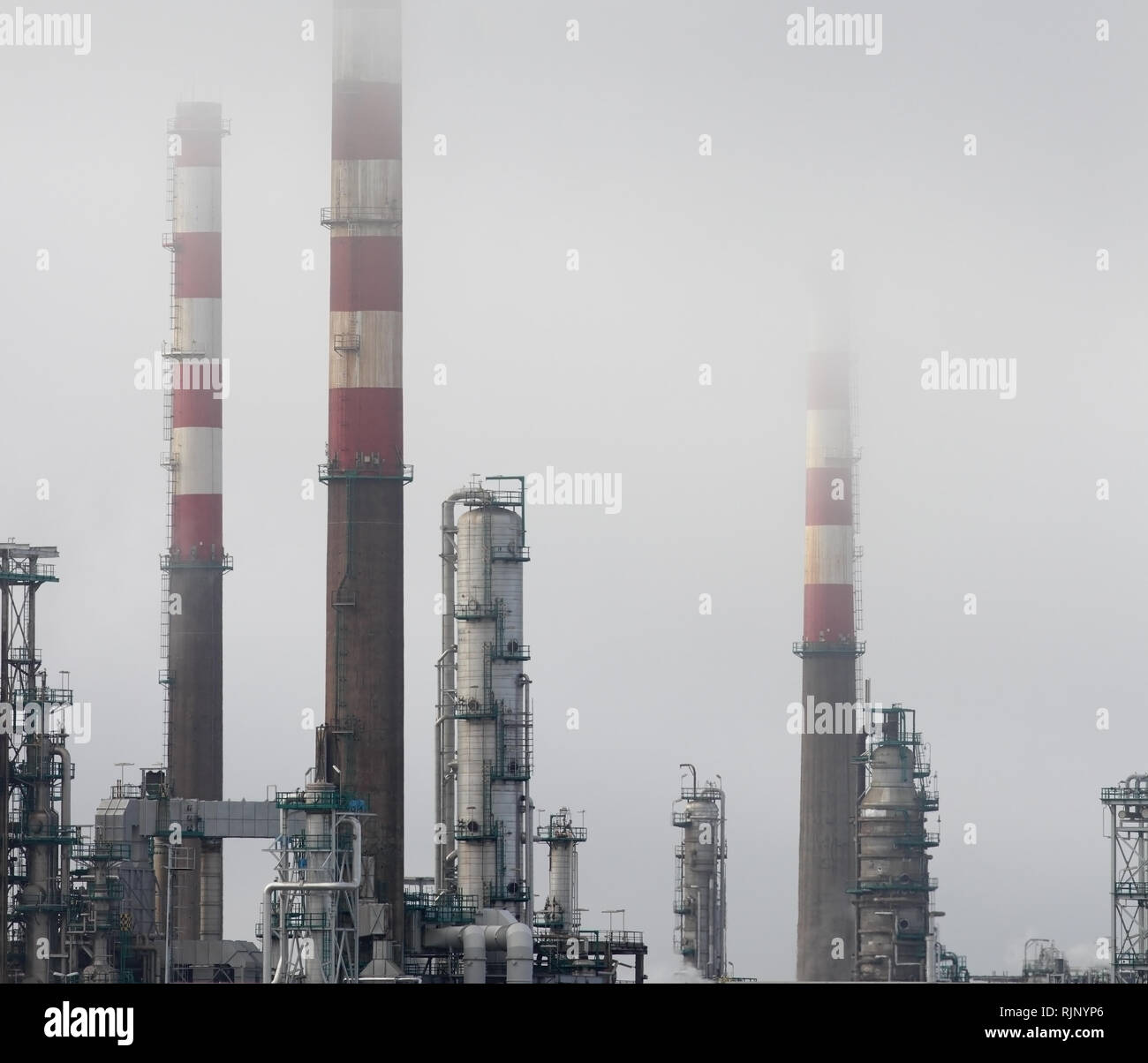 Les cheminées de la raffinerie de pétrole et des tours entre le brouillard Banque D'Images
