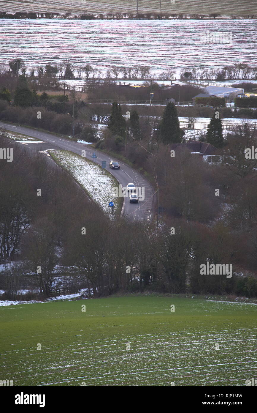 Voitures guidées sur une route rurale dans un paysage d'hiver, Bedfordshire, England, UK Banque D'Images