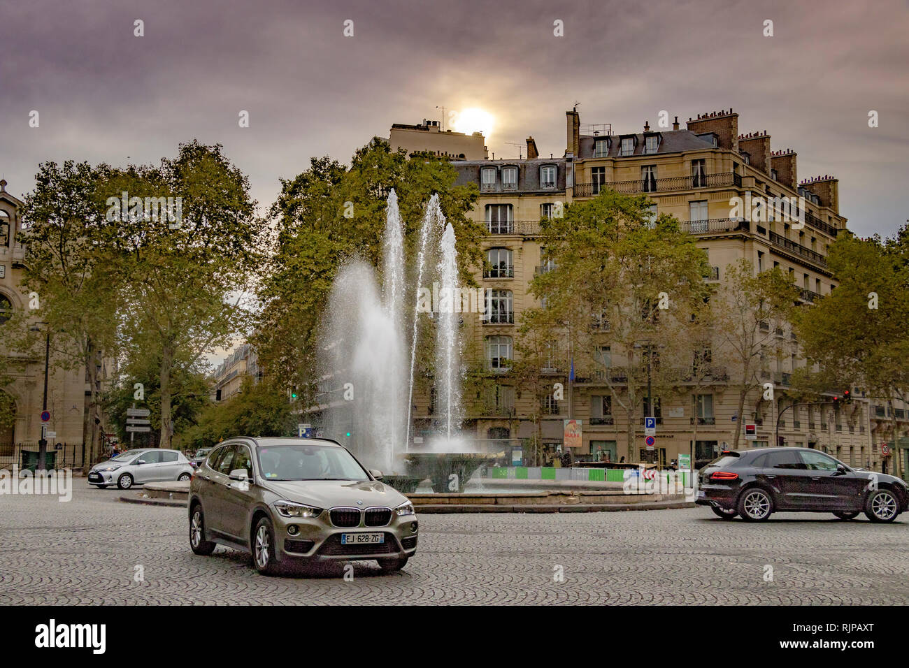 Les voitures qui circulent au-delà de la fontaine sur la Place Victor Hugo négligé par d'impressionnants appartements dans le 16ème arrondissement de belle , Paris , France Banque D'Images