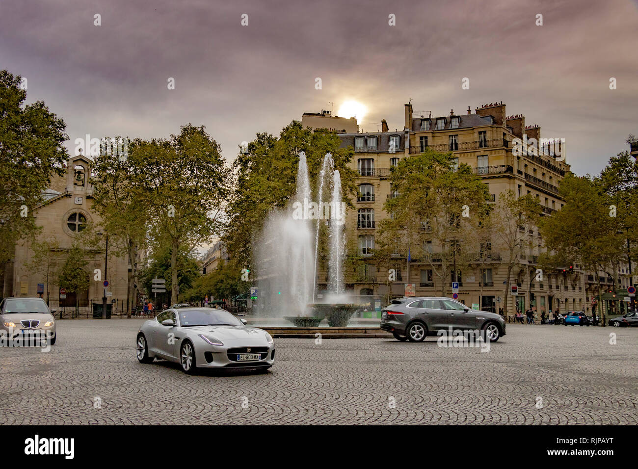 Les voitures qui circulent au-delà de la fontaine sur la Place Victor Hugo négligé par d'impressionnants appartements dans le 16ème arrondissement de belle , Paris , France Banque D'Images