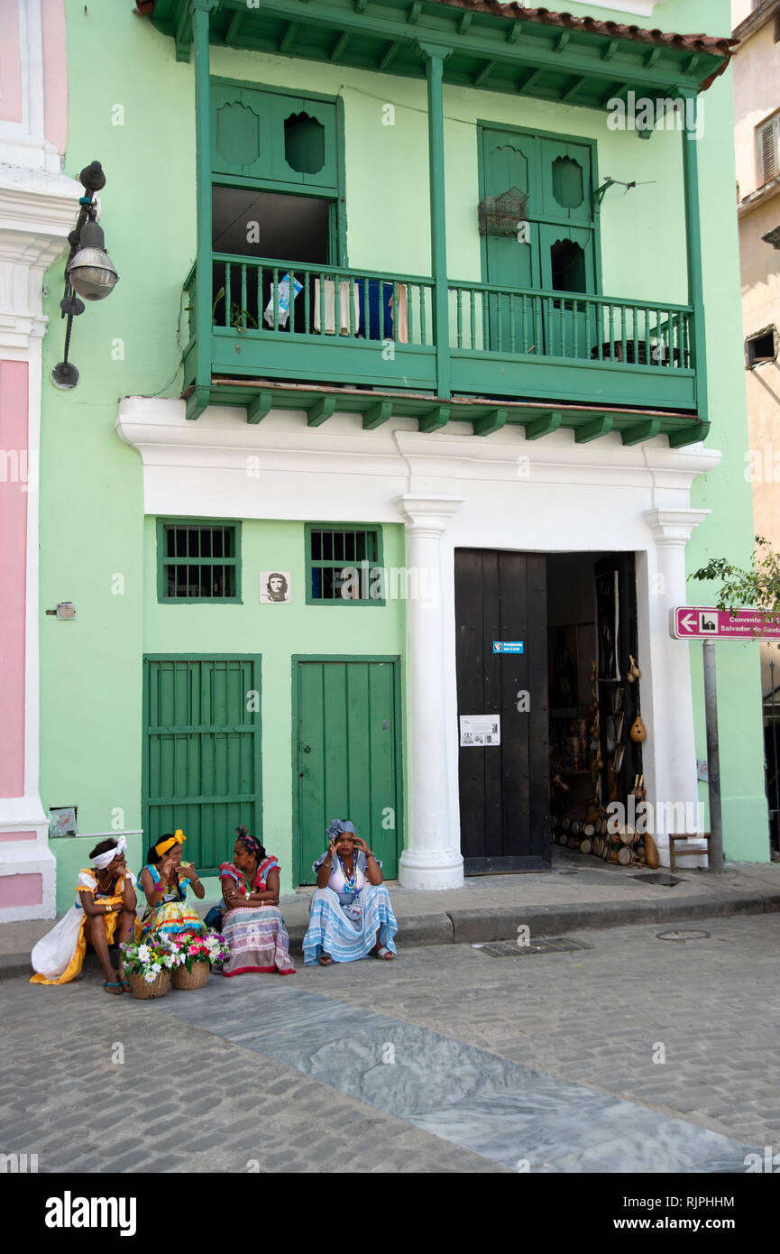 Quatre femmes cubaines habillé pour les touristes s'asseoir sur le pas d'un vieux bâtiment dans la Habana Vieja Cuba Banque D'Images