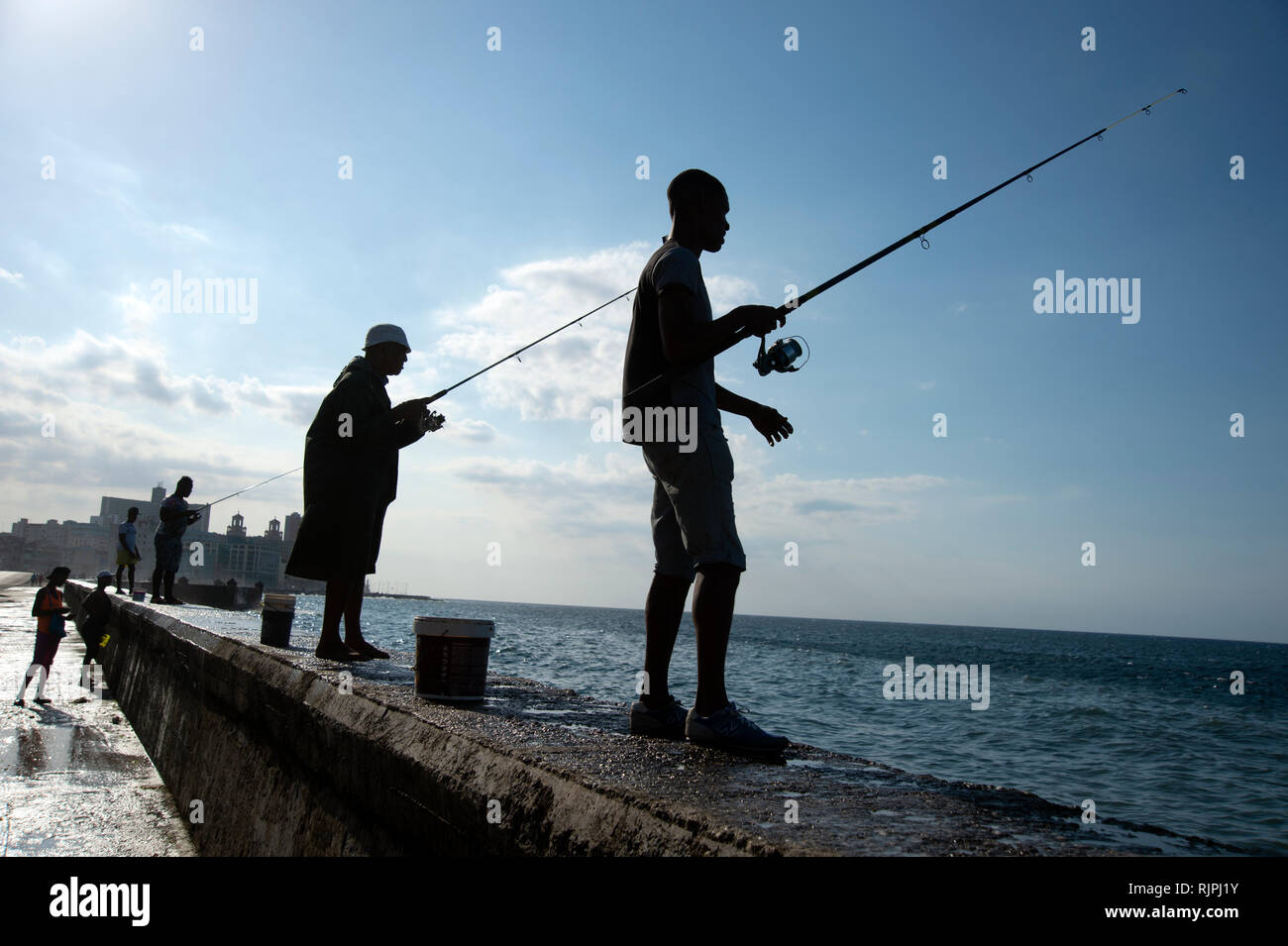 Quatre pêcheurs cubains qui se profile à partir de la digue sur le Malecon à La Havane Cuba Banque D'Images