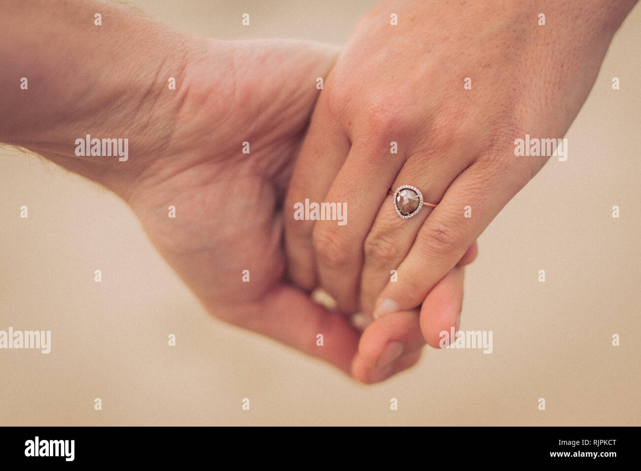 Close up horizontale photo d'un jeune couple à la plage avec l'accent sur l'anneau pendant une séance photo à la plage un jour nuageux. Banque D'Images