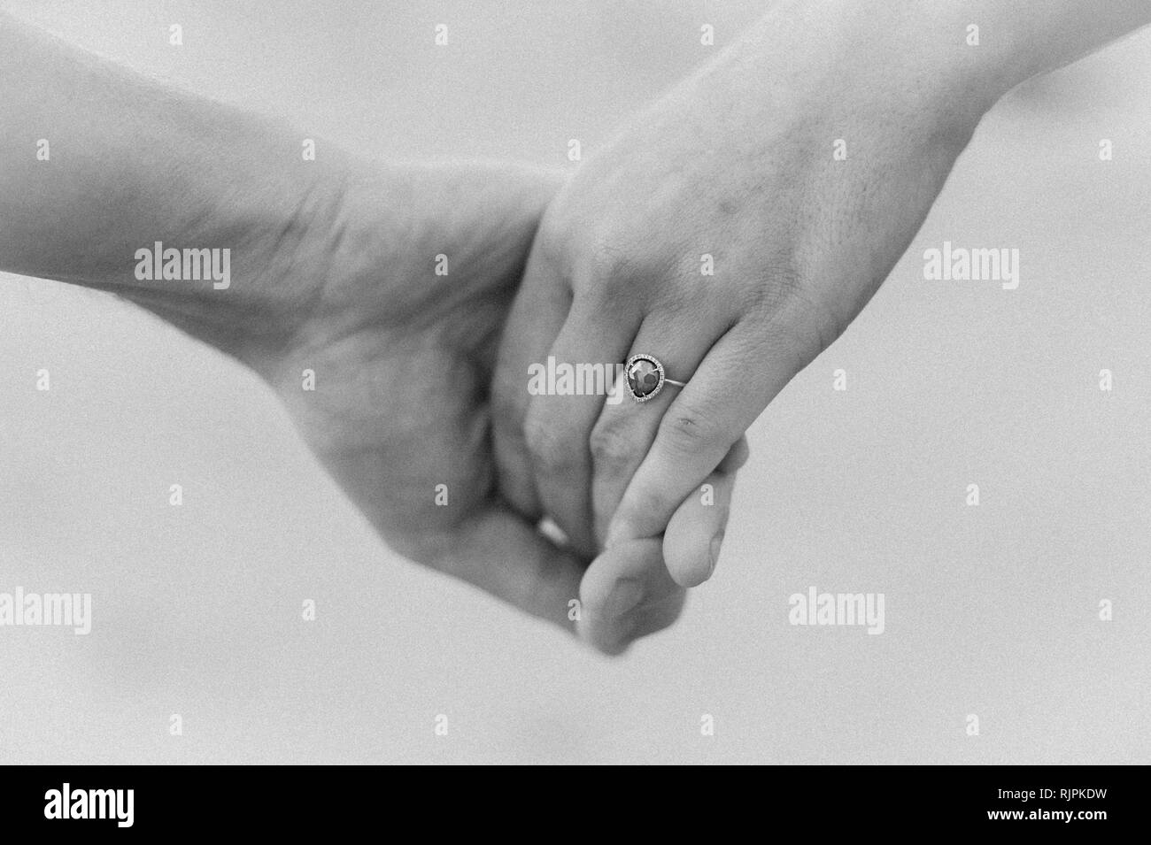 Close up horizontale photo d'un jeune couple à la plage avec l'accent sur l'anneau pendant une séance photo à la plage un jour nuageux. Banque D'Images