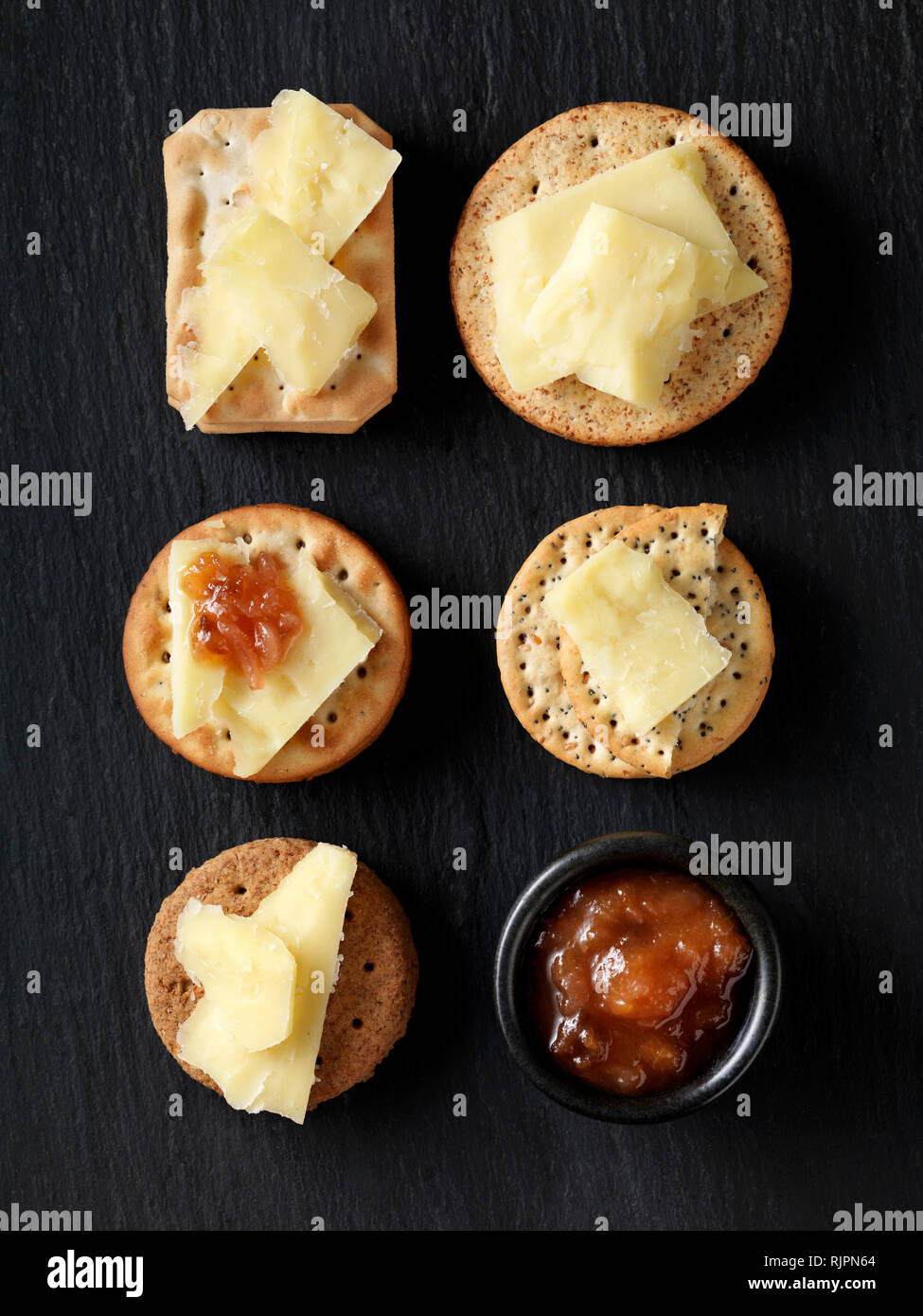 La vie encore de variété de craquelins au fromage avec le fromage cheddar et le chutney sur noir ardoise, overhead view Banque D'Images