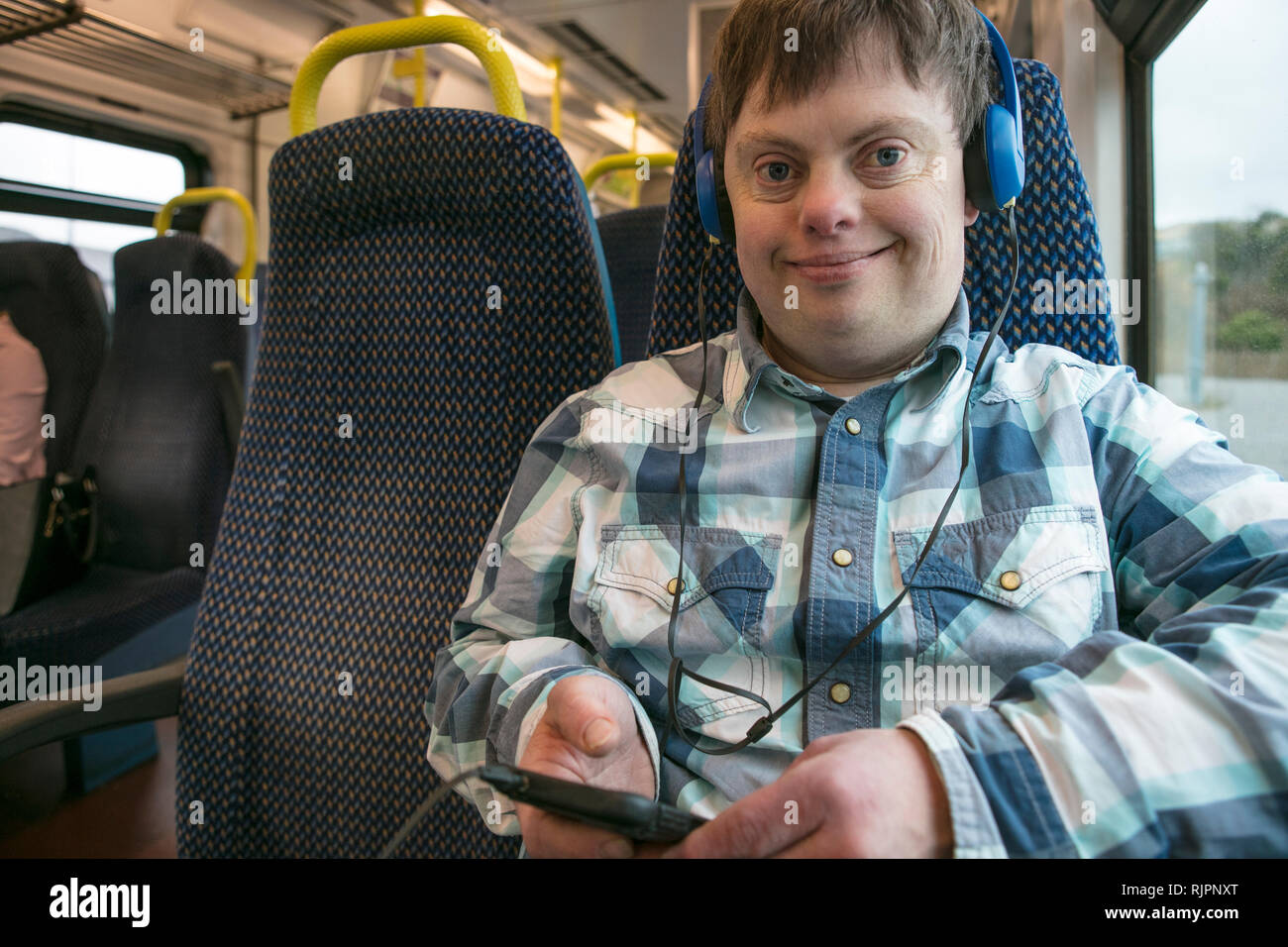 Avec le syndrome de l'homme avec l'aide d'écouteurs et un téléphone cellulaire sur le train Banque D'Images