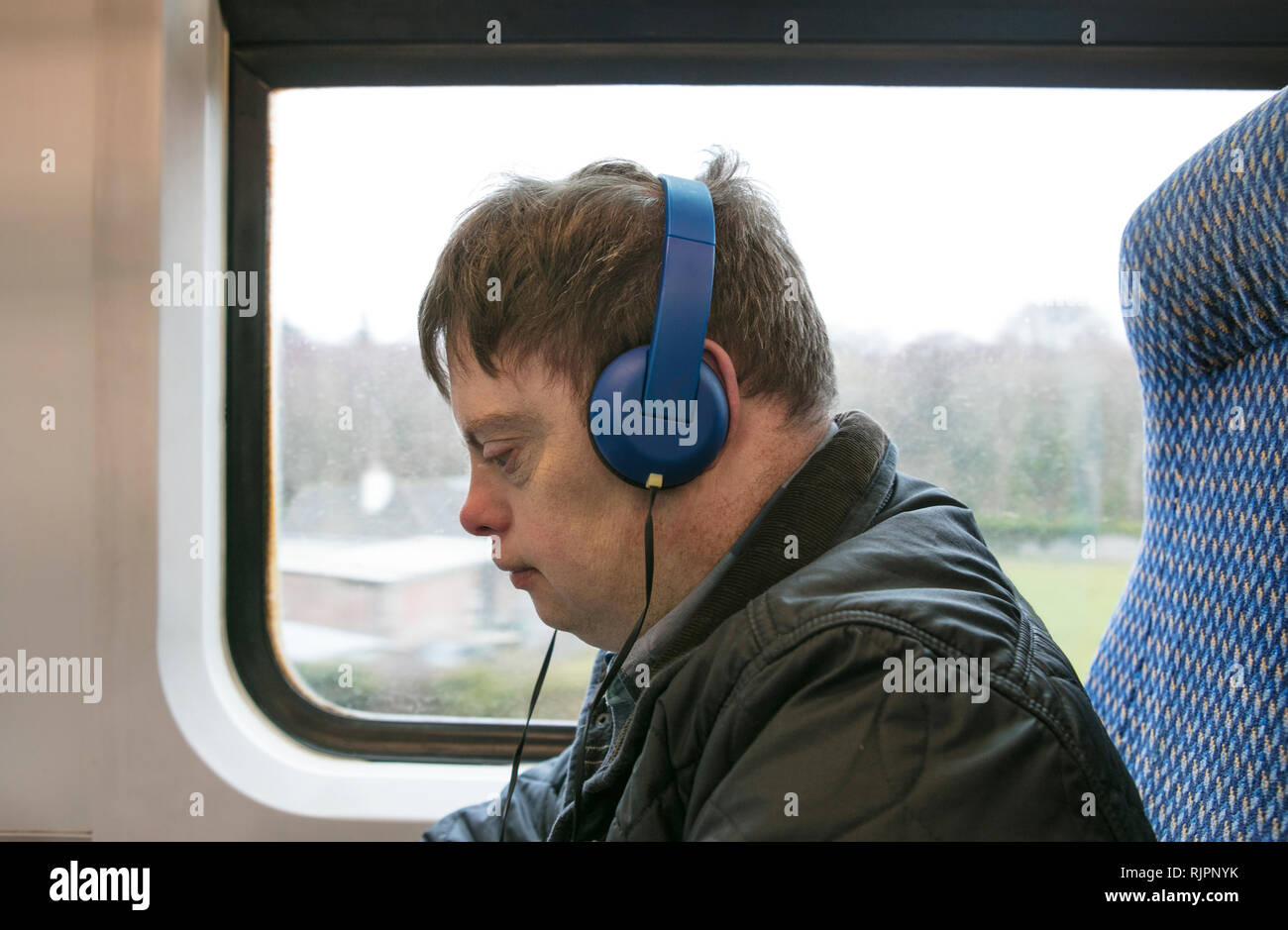 L'homme avec le syndrome de l'utilisation des écouteurs sur le train Banque D'Images