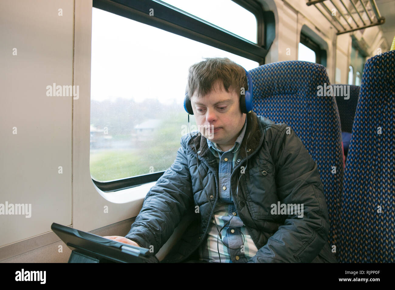 L'homme avec le syndrome de l'utilisation des écouteurs et tablette numérique sur le train Banque D'Images