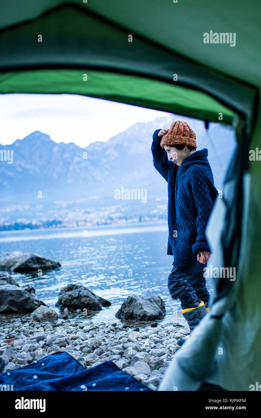 Camping au bord du lac, garçon sur vue de l'intérieur de tente, Onno, Lombardie, Italie Banque D'Images