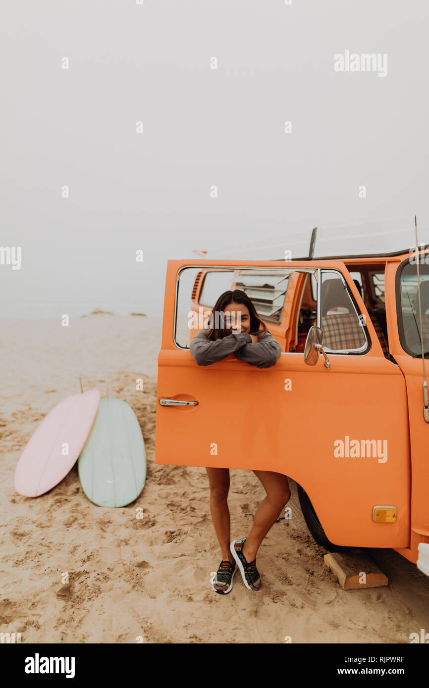 Young woman leaning on véhicule récréatif à fenêtre beach, portrait, Californie, Etats-Unis, Jalama Banque D'Images