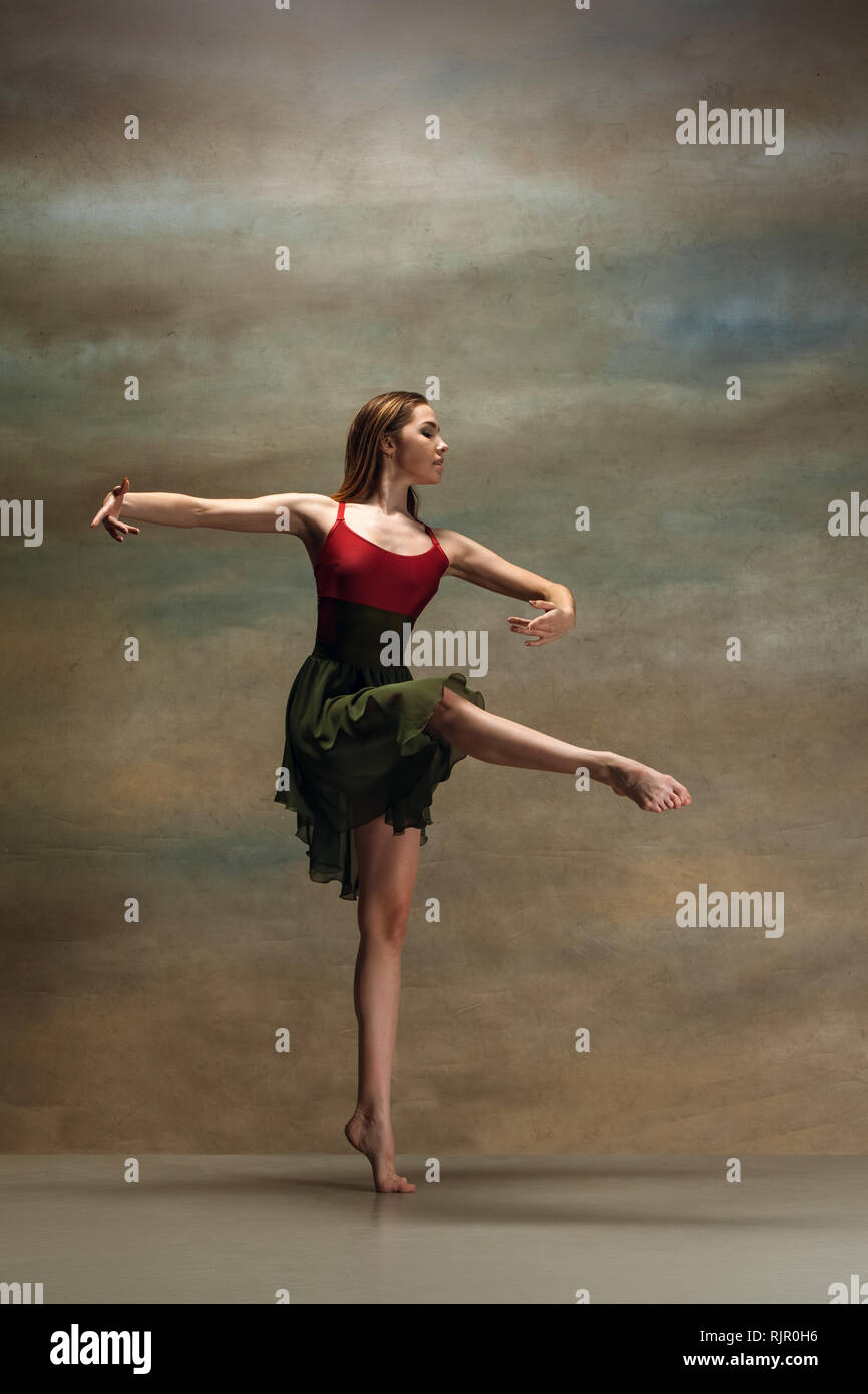 La jeune femme danse de style contemporain sur fond gris. Danseuse moderne au studio. L'élégance, la grâce et la performance concept Banque D'Images