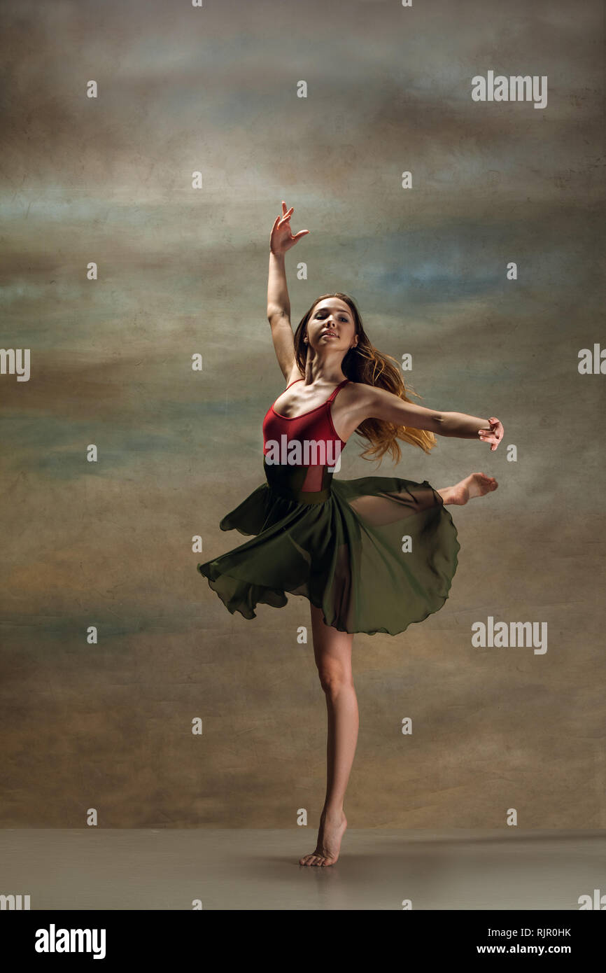 La jeune femme danse de style contemporain sur fond gris. Danseuse moderne au studio. L'élégance, la grâce et la performance concept Banque D'Images