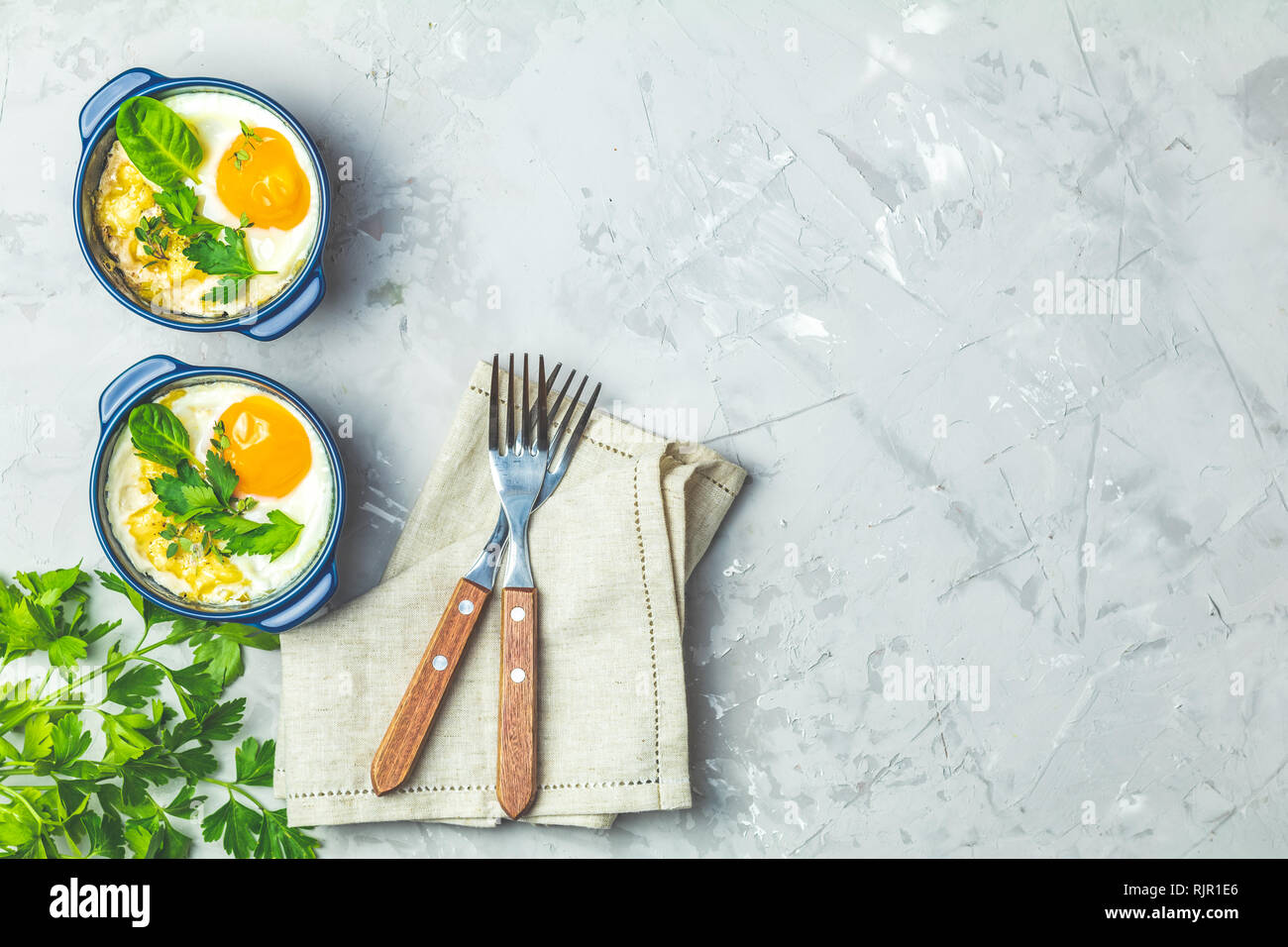 Oeufs cuits en bleu moules de cuisson en céramique. Cocotte de légumes et portionné oeufs dans un style italien ou français. Oeufs cocotte kokot petit-déjeuner. Haut Banque D'Images