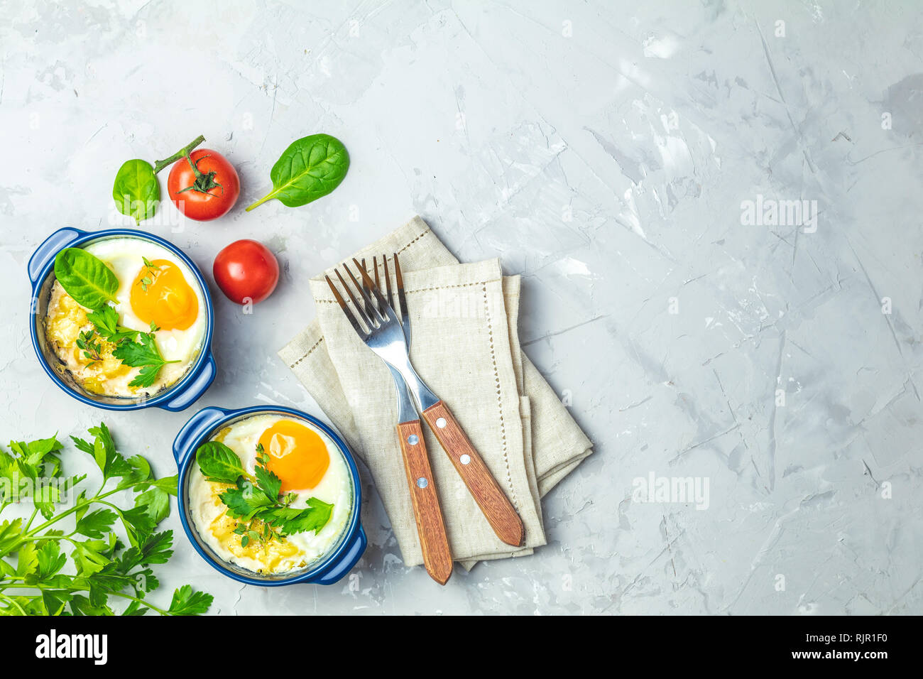 Oeufs cuits en bleu moules de cuisson en céramique. Cocotte de légumes et portionné oeufs dans un style italien ou français. Oeufs cocotte kokot petit-déjeuner. Haut Banque D'Images