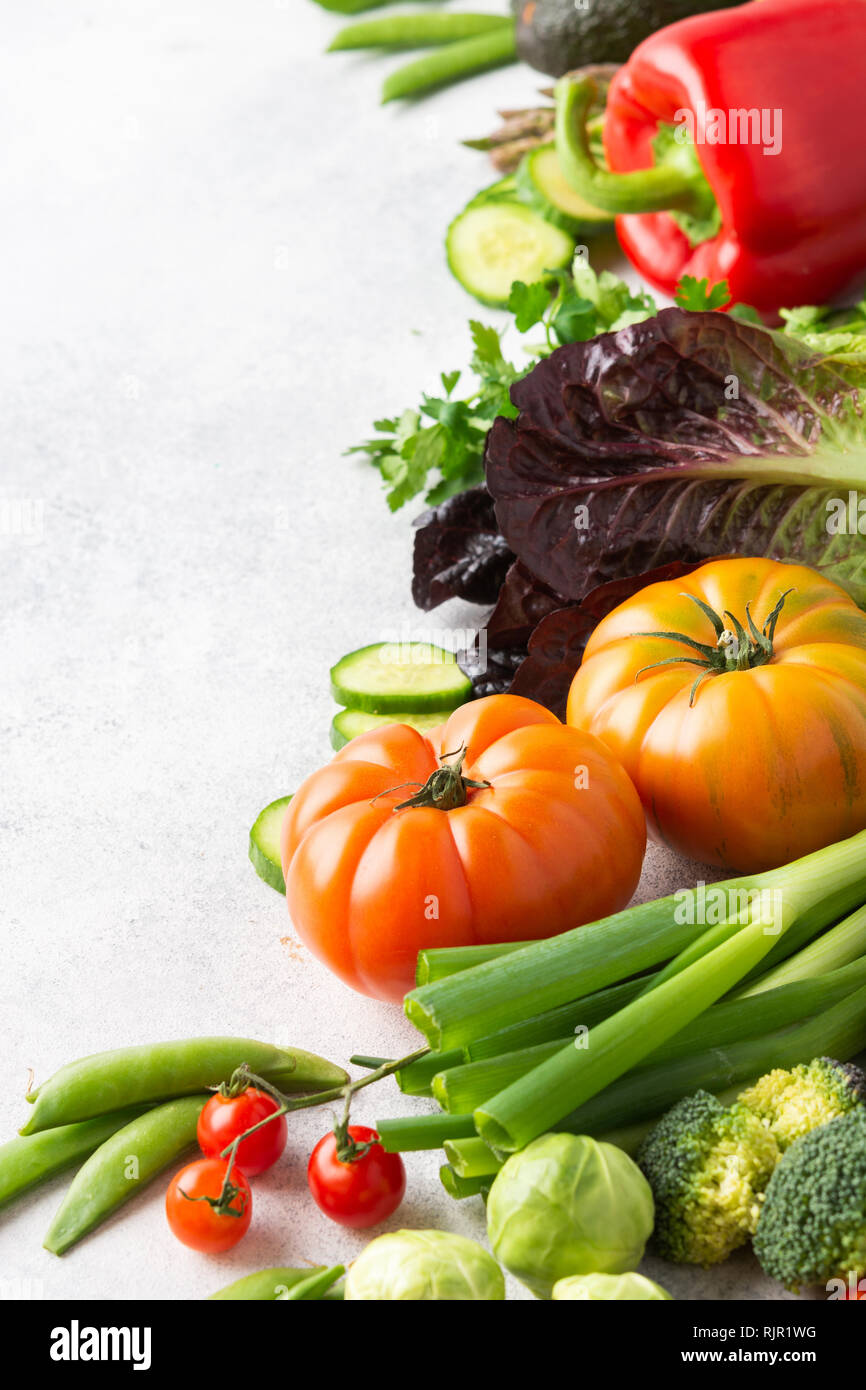 Des ingrédients frais pour la salade, tomates laitue persil Poivron Concombre avocat brocoli oignon pois sur le tableau blanc, copy space Banque D'Images