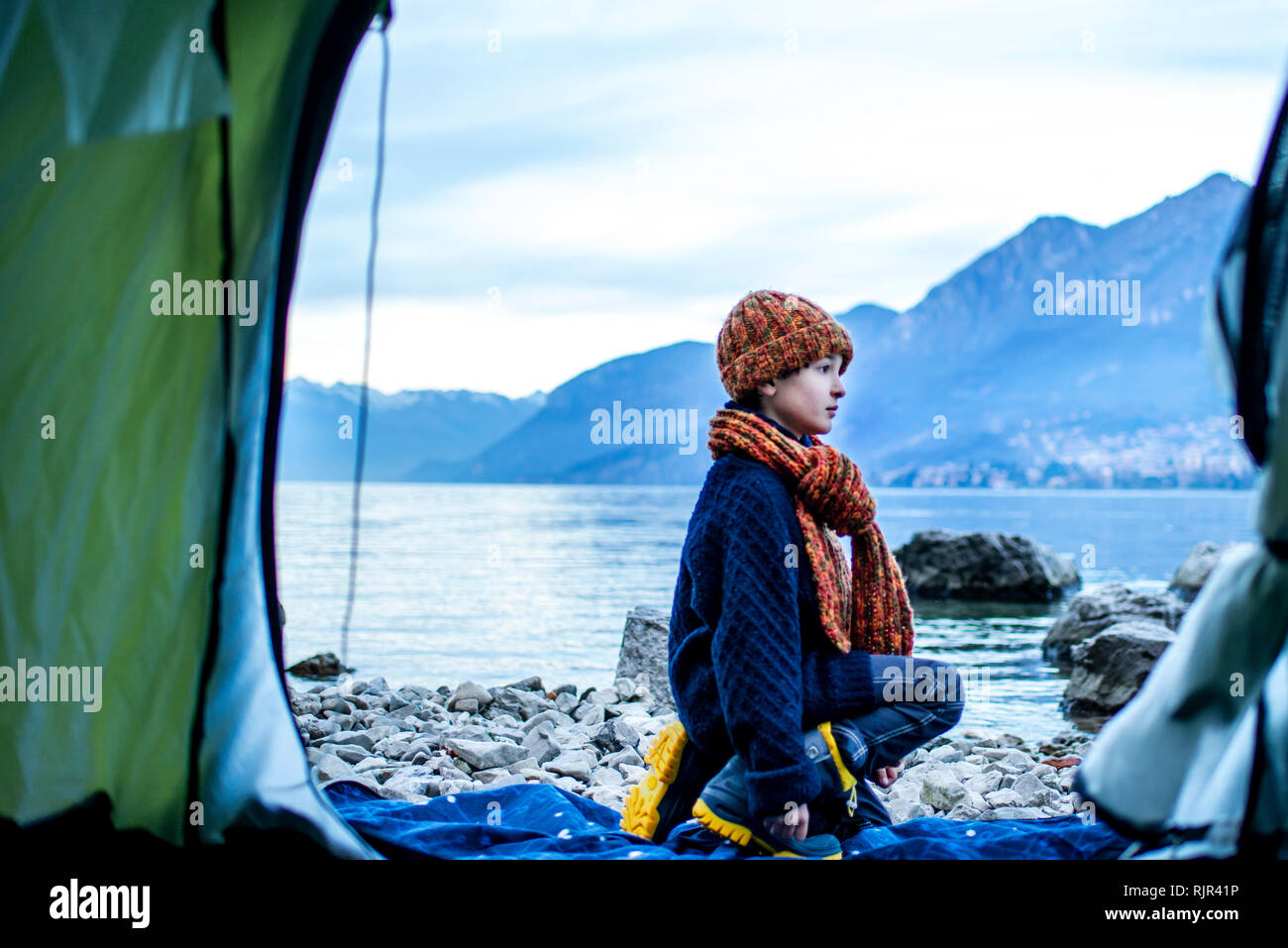 Garçon en dehors de tente sur un lac, le lac de Côme, Onno, Lombardie, Italie Banque D'Images