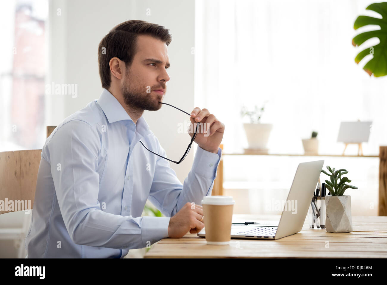 Thoughtful serious businessman perdue dans ses pensées au travail avec ordinateur portable Banque D'Images