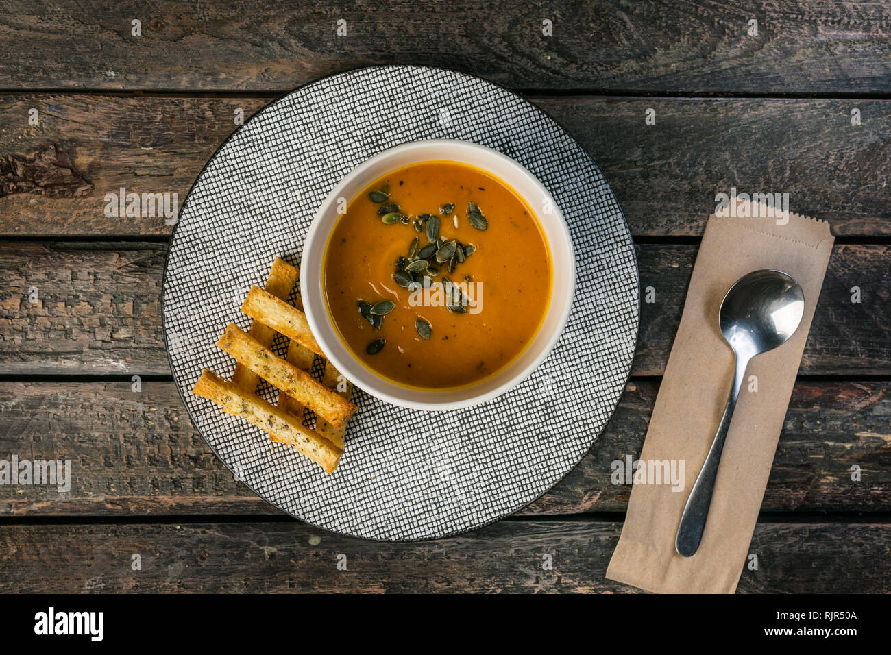 Crème de potiron soupe dans le bol en céramique avec les graines de citrouille et de croûtons sur fond de bois. Banque D'Images
