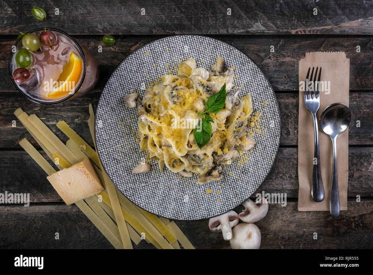 Les pâtes italiennes Les pâtes avec du fromage, poulet et champignons, servi sur la belle plaque en céramique avec les couverts. Décorées avec un verre de boissons Banque D'Images