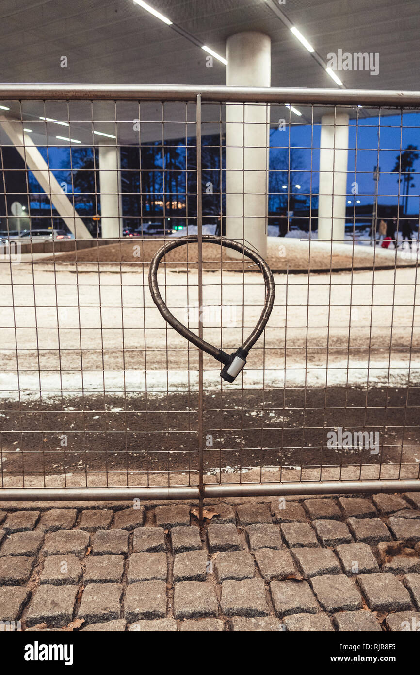 Cadenas de vélo verrouillé à une clôture en acier sur une journée d'hiver avec de la neige à un rond-point Banque D'Images