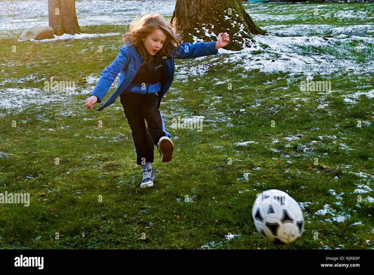 Jeune garçon aux cheveux longs à jouer avec un ballon de football Banque D'Images