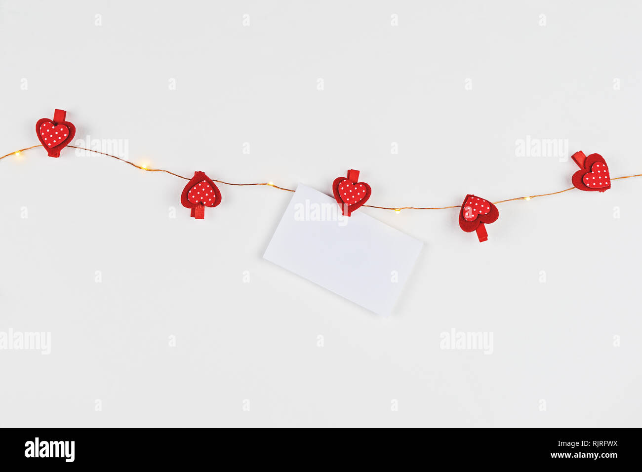La composition minimaliste avec fairy light et coeurs rouges pour fêter la Saint-Valentin sur fond blanc et de l'amour lettre modèle Banque D'Images