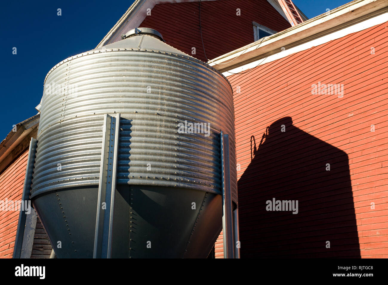 Gros plan du silo d'alimentation et de l'ombre contre un mur de la grange rouge dans la région de Kirby, Calédonie County, California, USA Banque D'Images