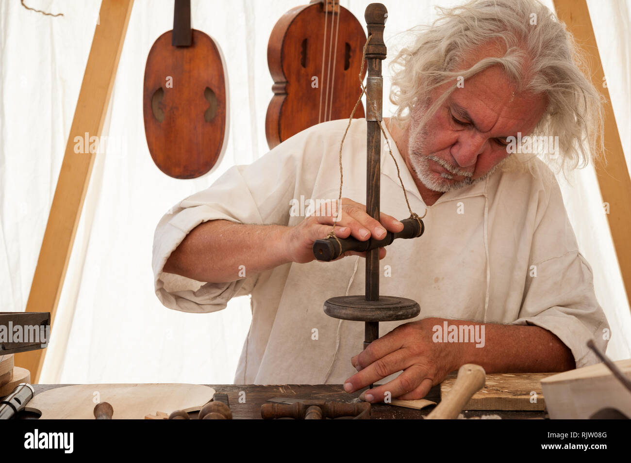 Le luthier travaillant sur la création d'un instrument à cordes. Il utilise une vieille perceuse manuelle Banque D'Images