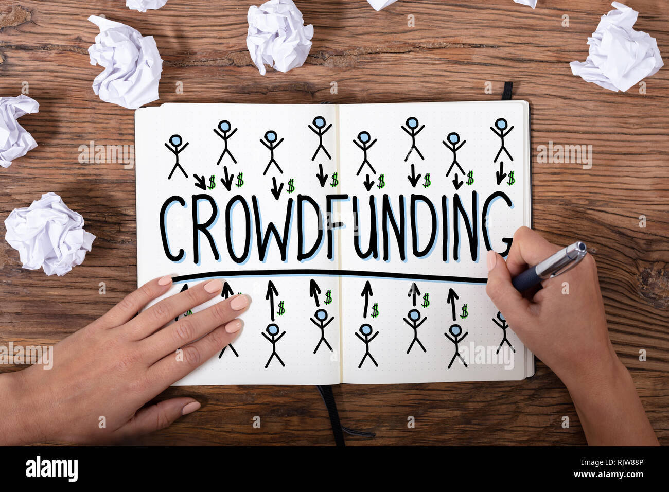 Une vue de dessus d'une Businesswoman's hand drawing Concept Crowdfunding texturé en bois sur 24 Banque D'Images