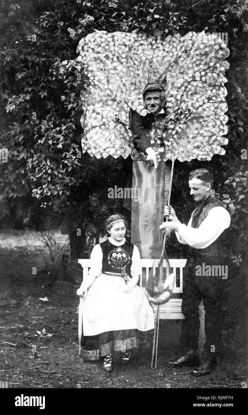 Couple, l'homme présente une femme avec du poisson pêché, l'homme dans un arbre artificiel observe la scène, ca. Années 1930, Bavière, Allemagne Banque D'Images