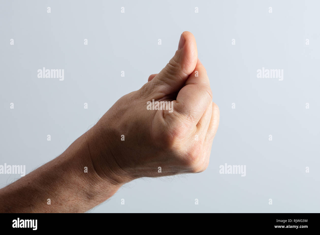 Close-up de la main de l'homme prendre son doigt contre l'arrière-plan gris Banque D'Images