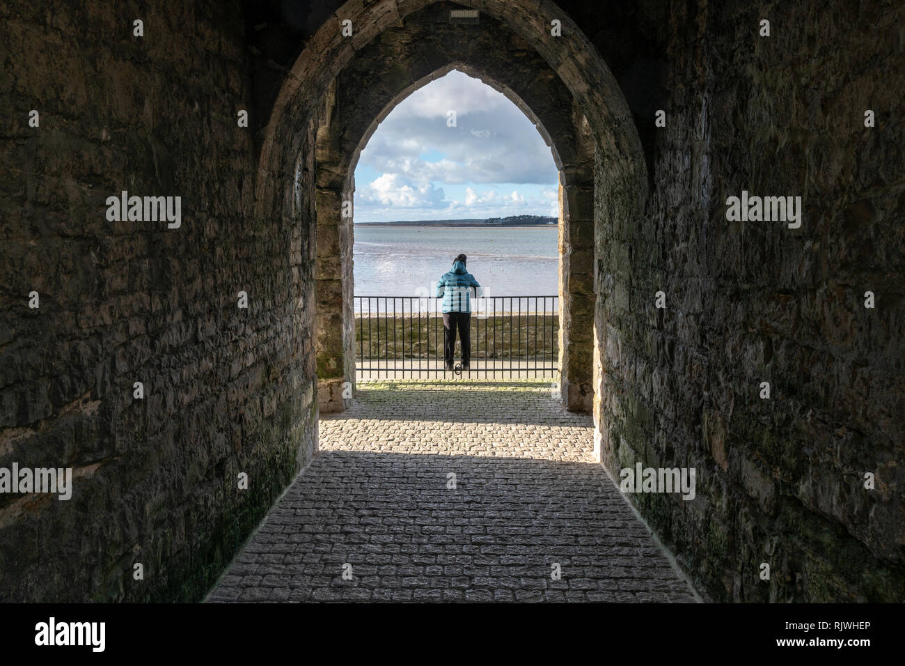 Une femme à l'extérieur, vers le détroit de Menai dans le Nord du Pays de Galles d'une arche à Caernarfon. Banque D'Images