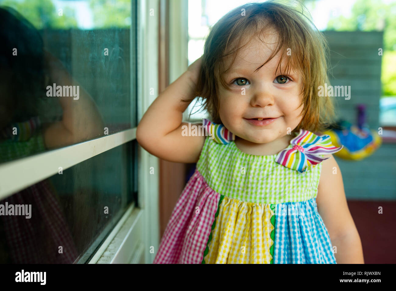Un Bebe Fille Portant Une Robe Soleil Arc En Ciel Sourit A La Camera Dans Une Photo Photo Stock Alamy
