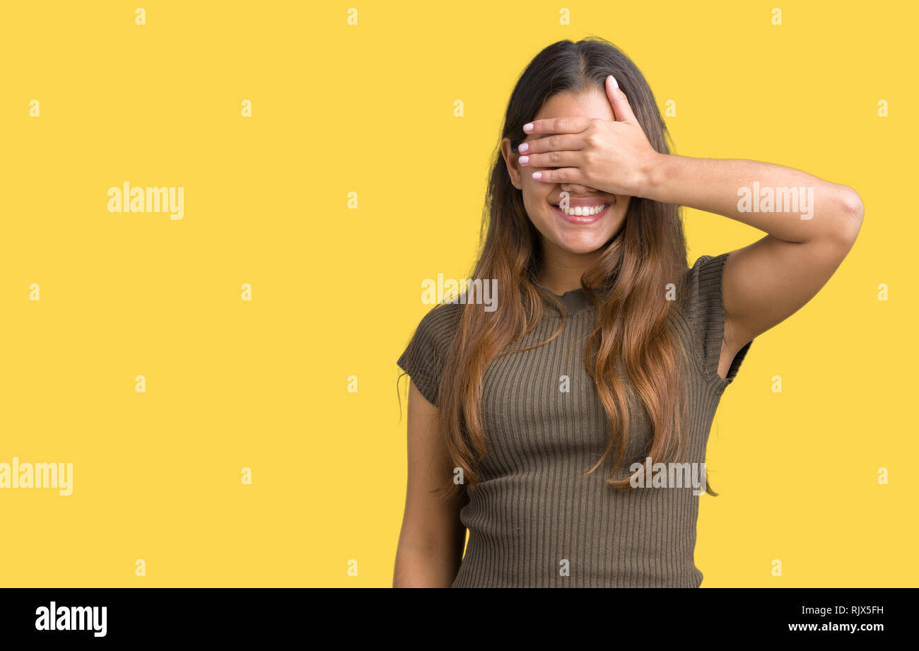 Belle jeune femme brune sur fond isolé sourire et rire avec la main sur le visage pour les yeux pour une surprise. Concept aveugle. Banque D'Images