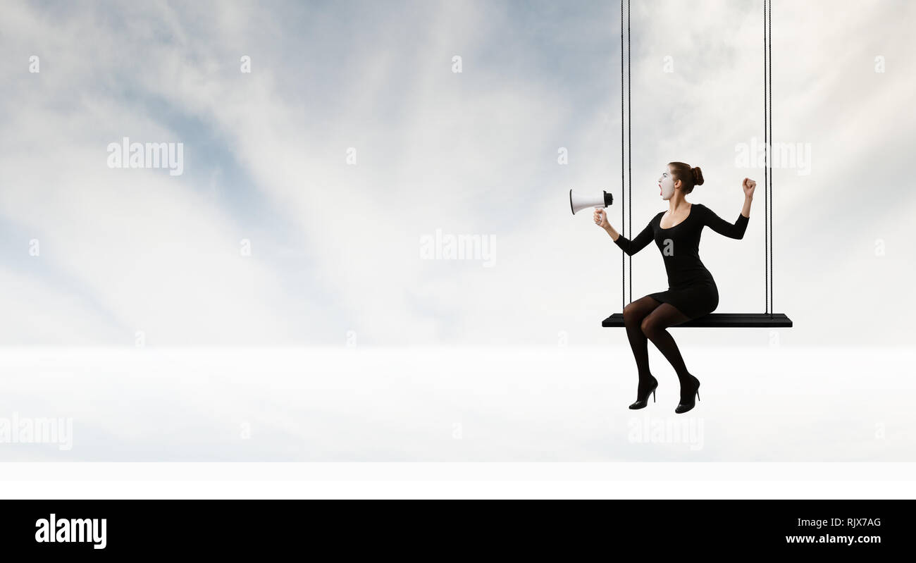 Femme mime dans un costume noir assis sur swing. Technique mixte Banque D'Images