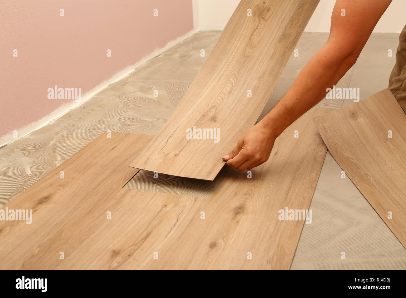Travaux de pose de parquet. L'installation d'un nouveau travailleur plancher de carreaux de vinyle. Banque D'Images