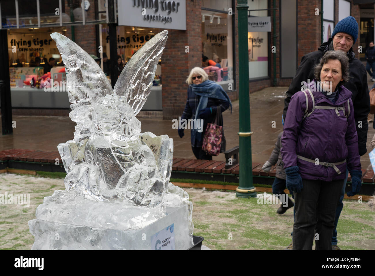 Les hommes et les femmes qui passent se latent étrangement de la sculpture sur glace à hayon Dragon, Myths and Legends York Ice Trail, North Yorkshire, Angleterre, Royaume-Uni. Banque D'Images