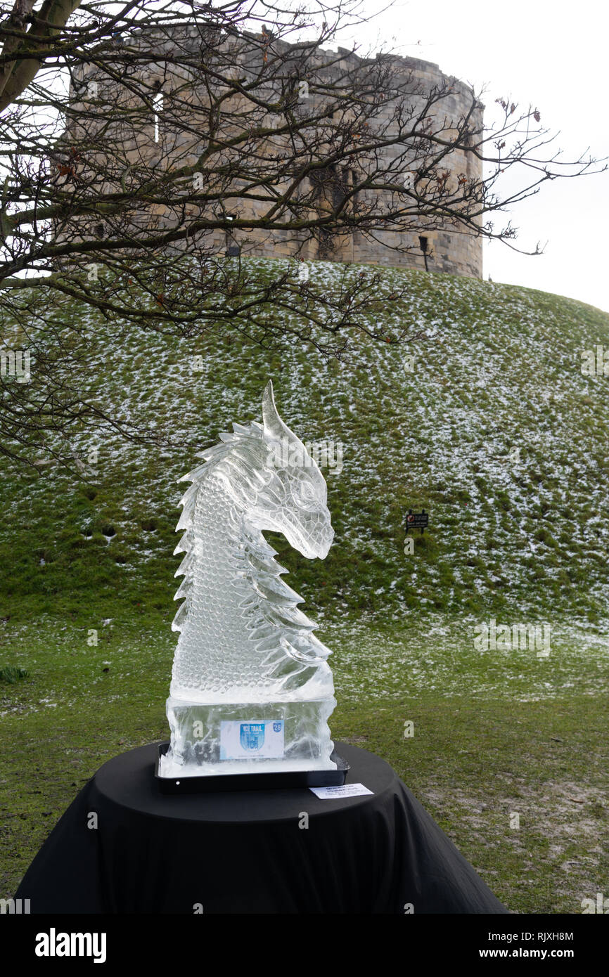 Sculpture sur glace mythique de Dragon's Head avec la tour Clifford en arrière-plan le long de la piste de glace de York, North Yorkshire, Angleterre, Royaume-Uni. Banque D'Images